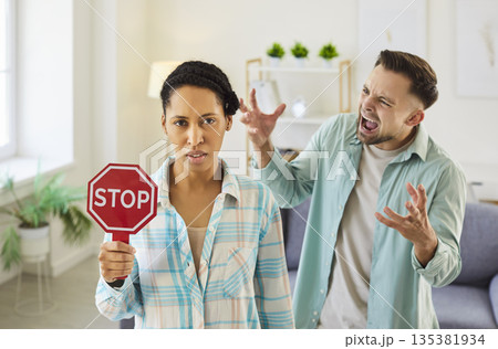 Woman holding STOP sign while her partner yells at her, setting boundary against abuse Woman holding STOP sign while her partner yells at her, setting boundary against abuse 135381934