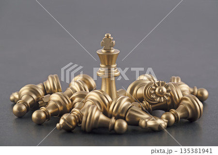 Victorious golden king with group of lying chess pieces 135381941