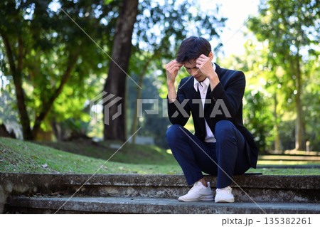Office man stressed and sitting on outdoor steps in a green park 135382261