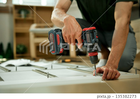 Closeup man is working with furniture assembly using electric screwdriver Closeup man is working with furniture assembly using electric screwdriver 135382273