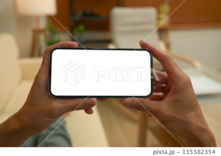Close up view of a man using blank screen smartphone at living room 135382354