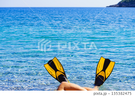 Feet in flippers fins on sea shore 135382475