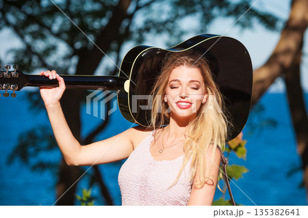 Blonde woman with acoustic guitar on seaside 135382641