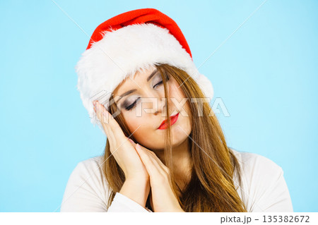 Woman in santa hat being sleepy Woman in santa hat being sleepy 135382672