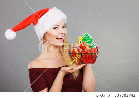 Santa woman holding shopping cart with christmas gifts Santa woman holding shopping cart with christmas gifts 135382742