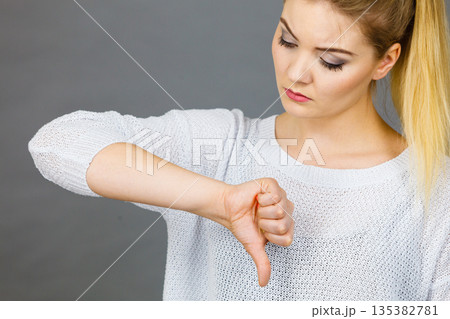 Sad woman showing thumb down gesture 135382781