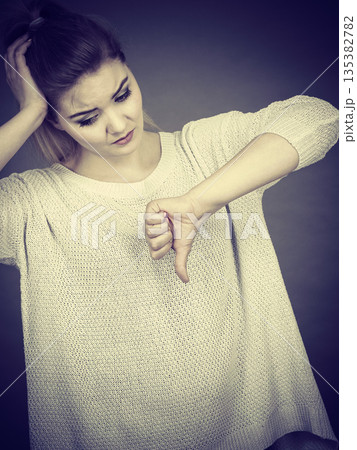 Sad woman showing thumb down gesture Sad woman showing thumb down gesture 135382782