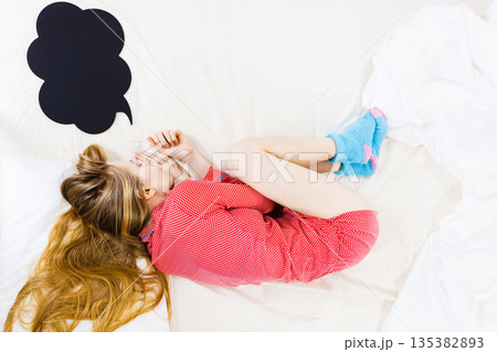 Young woman lying on bed wearing pajamas 135382893