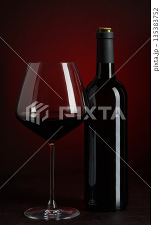 Red Wine Bottle and Glass on Dark Red Gradient Background. Elegant Still Life Red Wine Bottle and Glass on Dark Red Gradient Background. Elegant Still Life 135383752