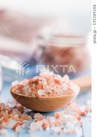 Pink Himalayan salt on wooden spoon on blue table. Pink Himalayan salt on wooden spoon on blue table. 135384108