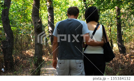 Happy couple walking along path at summer forest. Romantic pair going along trail at wild woodland. Lovers spending time together at nature. Concept of love and happiness. Slow motion Happy couple walking along path at summer forest. Romantic pair going along trail at wild woodland. Lovers spending time together at nature. Concept of love and happiness. Slow motion 135384132
