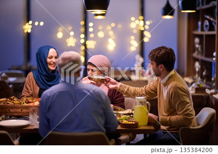 Family enjoys iftar at a restaurant with Ramadan decorations and warm lighting during the holy month 135384200
