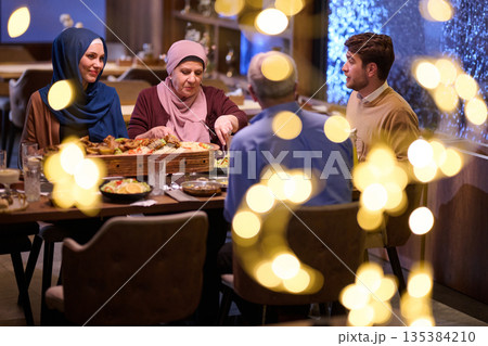 Muslim family enjoys iftar together in a restaurant decorated for Ramadan celebration Muslim family enjoys iftar together in a restaurant decorated for Ramadan celebration 135384210