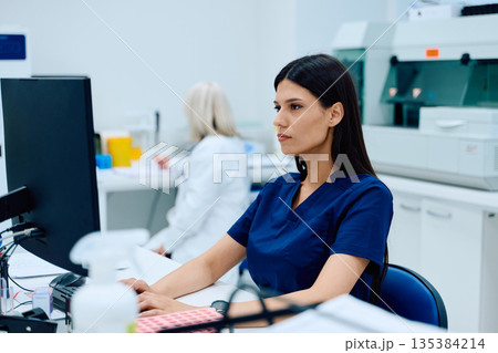 Medical laboratory technician focusing on data analysis in a modern lab setting during the day Medical laboratory technician focusing on data analysis in a modern lab setting during the day 135384214