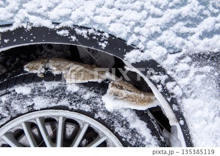 Road salt of the wheel of a snow covered car 135385119