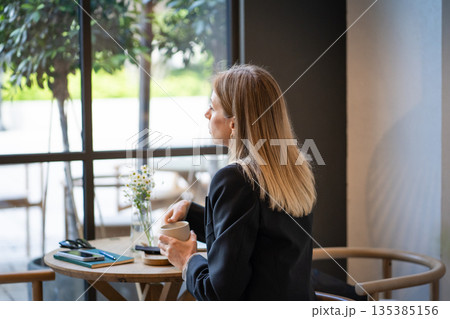 Pondering relaxed businesswoman sitting at cafe looking at window and thinking about work plans. Pondering relaxed businesswoman sitting at cafe looking at window and thinking about work plans. 135385156