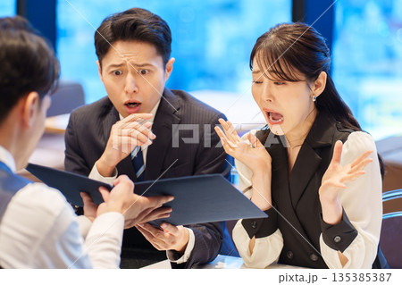 レストランのメニューを見て驚くカップル 135385387