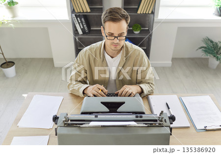 Writer typing at vintage typewriter in office, top view of journalists workflow Writer typing at vintage typewriter in office, top view of journalists workflow 135386920