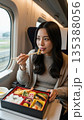新幹線と駅弁食べる女性 135388056