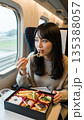 新幹線と駅弁食べる女性 135388057