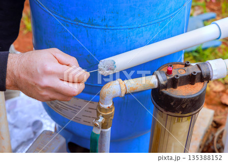 Worker performs maintenance on water filtration system near blue tank Worker performs maintenance on water filtration system near blue tank 135388152