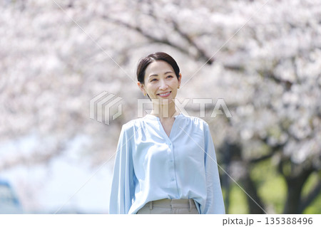 満開の桜と散歩する女性 135388496