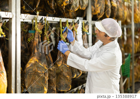 Man employee checks jamon. Quality control Man employee checks jamon. Quality control 135388917