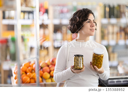 Adult woman choosing olives in grocery store Adult woman choosing olives in grocery store 135388932