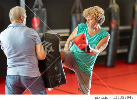 Man landing kick on padded shield during self-defense training Man landing kick on padded shield during self-defense training 135388945