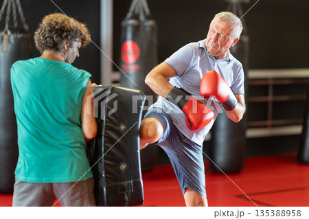 Elderly man striking shield in self-defense drill 135388958
