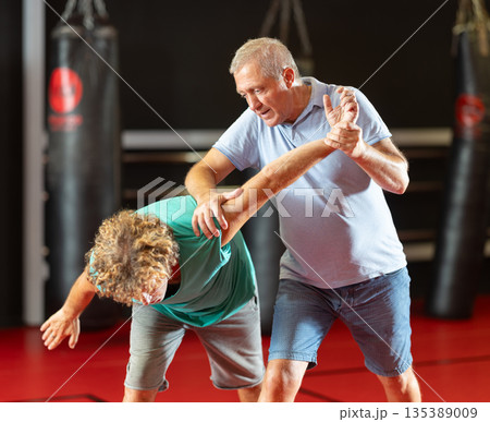 Focused senior man grappling in amateur wrestling session 135389009