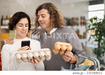 Woman and man scanning eggs in store Woman and man scanning eggs in store 135389011