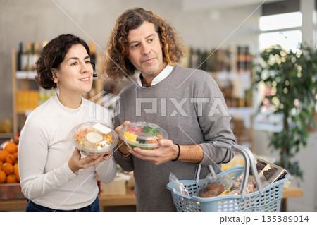 In store, spouses near counter are looking at poke salad In store, spouses near counter are looking at poke salad 135389014