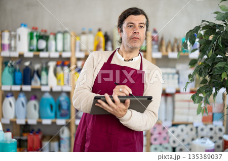 Man seller, with tablet in hands, make inventory in store. 135389037