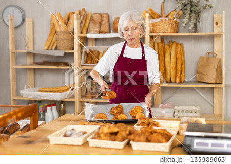 Senior woman seller of bakery store is standing in trading floor, waiting for visitors 135389063
