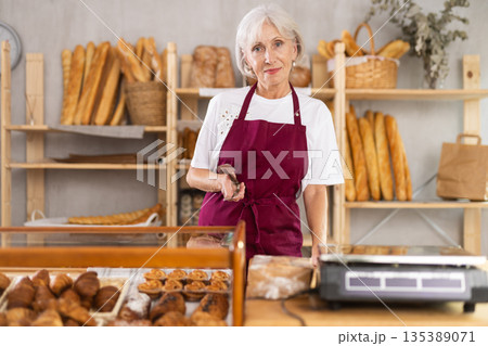 Mature saleswoman holding a service clip in bakery 135389071