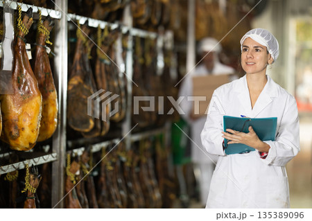 Female employee of the jamon factory conducts inventory and quality control Female employee of the jamon factory conducts inventory and quality control 135389096