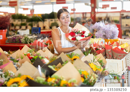 Young girl holding bouquet of flowers in large plants market Young girl holding bouquet of flowers in large plants market 135389250
