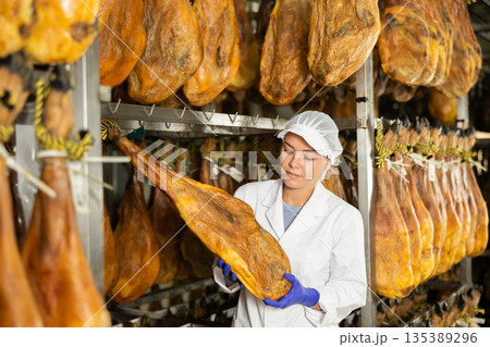 female worker checks the quality of jamon in a factory 135389296