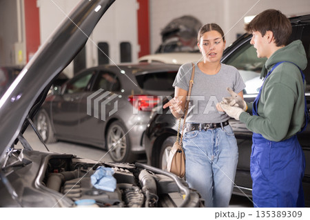 Woman car owner explains car engine problem to a car service mechanic 135389309