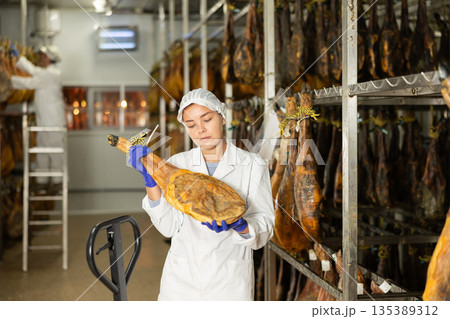 Girl employee checks jamon. Quality control Girl employee checks jamon. Quality control 135389312