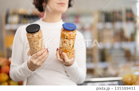 In store, customers near counter are looking at canned beans In store, customers near counter are looking at canned beans 135389431