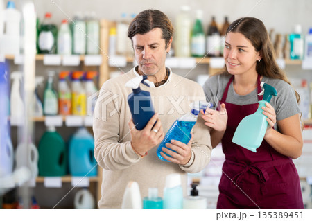 Female salesperson helps man choose best spray glass cleaner Female salesperson helps man choose best spray glass cleaner 135389451