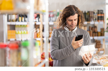 Adult man scanning qr code for yogurt Adult man scanning qr code for yogurt 135389515