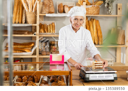 Elderly woman seller weighs piece of cake Elderly woman seller weighs piece of cake 135389550