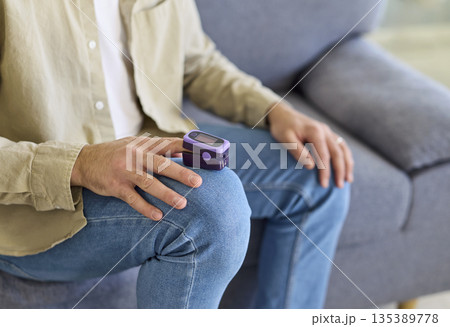 Man using pulse oximeter on finger to monitor oxygen saturation in blood at home Man using pulse oximeter on finger to monitor oxygen saturation in blood at home 135389778