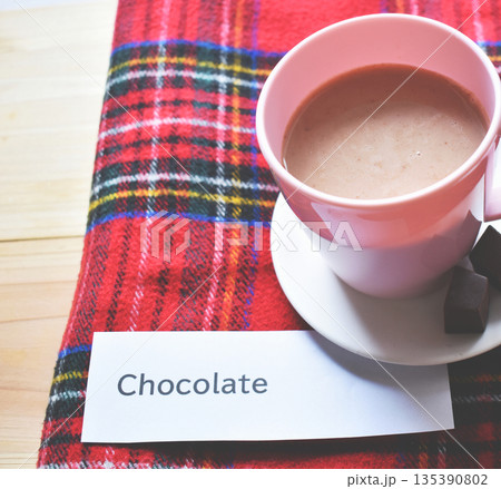タータンチェックのマフラーの上のホットチョコレートのクローズアップ 135390802