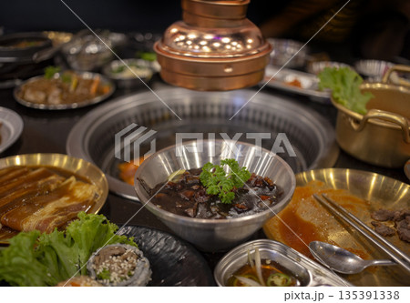 Authentic Korean BBQ set with various side dishes and grilled meat on a restaurant table. Concept for Asian dining culture, food tourism, and delicious gourmet experience 135391338