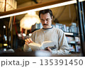 Focused man booklover reading book in modern bookshop, flipping through pages, enjoying novel. 135391450