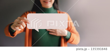 Smiling Woman holding blank Bubble Speech. Symbol of free speech, empowerment 135391648